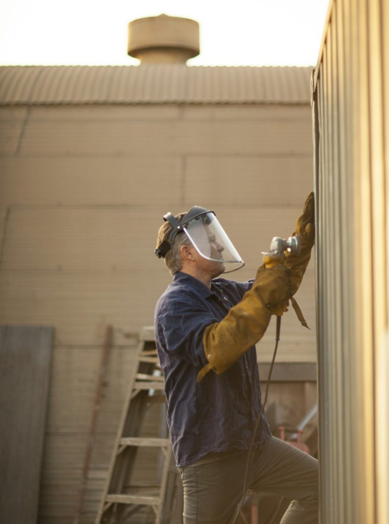 Welder using power tool on shipping container Welder using power tool on shipping container