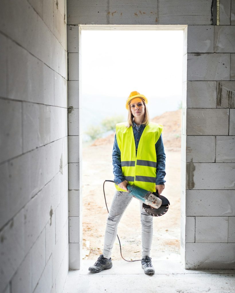 Young woman worker with electric tool on the construction site. Young woman worker with electric tool on the construction site.